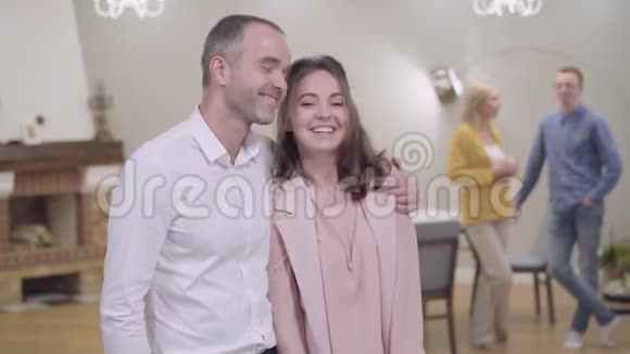 积极的白人父亲拥抱他美丽的女儿微笑他的妻子和女婿在后台聊天视频的预览图