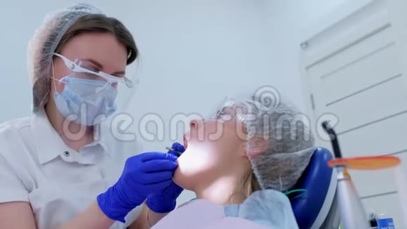 牙科医生在超声波清洗时将棉塞放入女性口腔干牙中视频的预览图