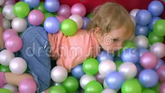 快乐的学龄前儿童在多种颜色的球池中玩得开心托儿所视频的预览图