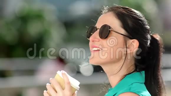 可爱的黑发女人在阳光明媚的白天在户外喝茶放松视频的预览图