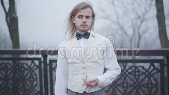 时尚的白人留着长发和胡须站在桥上检查老式手钟的时间帅哥视频的预览图