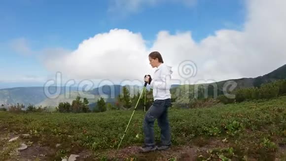 在山中行走带着徒步旅行杆的女孩在山上跑得很高视频的预览图