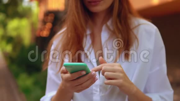 穿着白色衬衫和蓝色耳机的女性使用手机视频的预览图