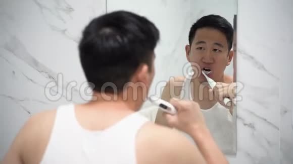 亚洲男人用电动牙刷清洁牙齿视频的预览图
