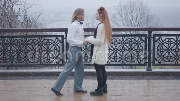 侧面的时尚男孩在优雅的复古风格的衣服屈膝并向他的女朋友求婚青年视频的预览图