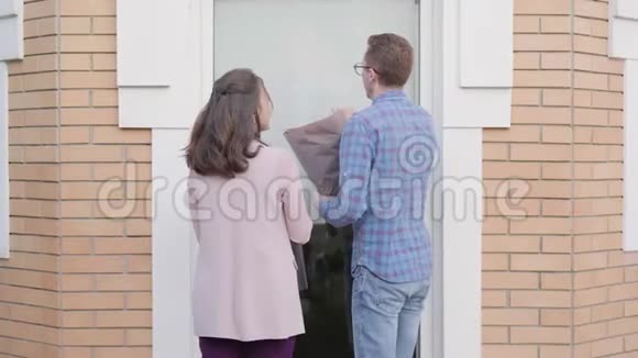 年轻的白种人夫妇带着一束红玫瑰和蛋糕来到门口紧张的红头发视频的预览图