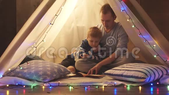小男孩在家里的儿童帐篷里玩父亲在读童话快乐的白种人小孩在游戏室视频的预览图