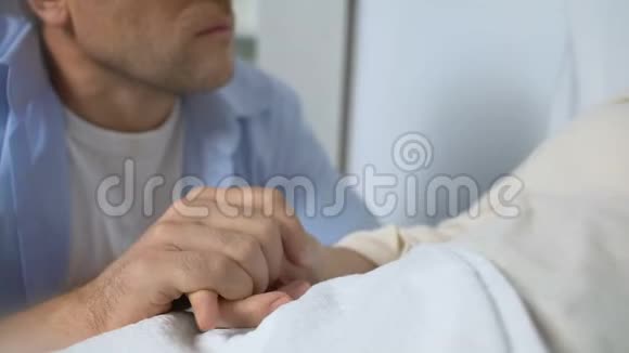 坐在残疾母亲病床旁的男子感到不安健康问题视频的预览图