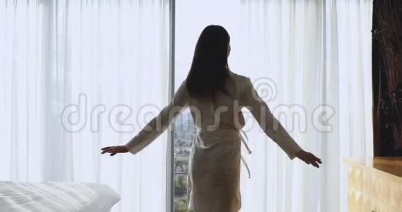 快乐的女人在卧室里独自伸出双臂旋转视频的预览图