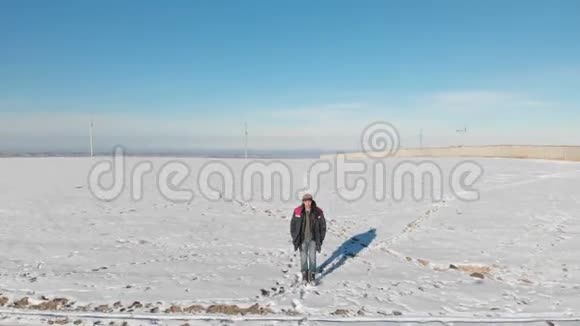 在一个冬天阳光明媚的日子里跟随着穿着牛仔裤和温暖鞋子男人在雪地里散步从上面可以看到空中景色视频的预览图