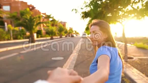 跟着我快乐的年轻女子拉着小伙子手牵着手在阳光明媚的日子里奔跑慢动作视频的预览图