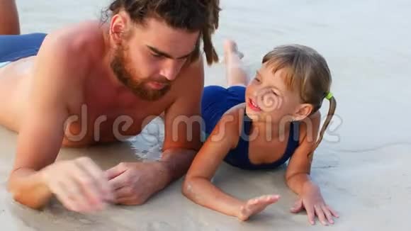 父女俩躺在海边的沙滩上视频的预览图