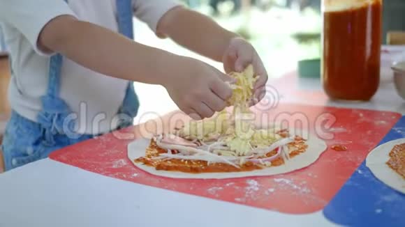 快乐的孩子们在厨房准备自制披萨小女孩把奶酪放在披萨面团上家庭娱乐和烹饪c视频的预览图