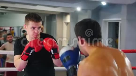 拳击两个挥汗如雨的男人在健身房里打拳击其中一个穿着黑色T恤视频的预览图