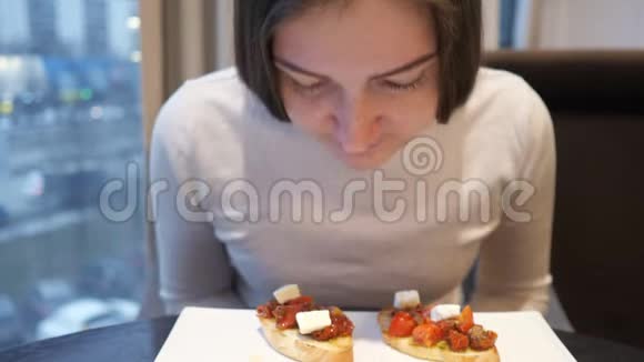 在窗户的背景上吃奶酪和西红柿的年轻女人视频的预览图