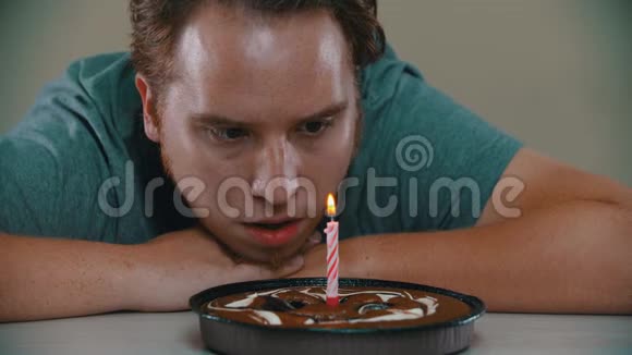 悲伤的人正在把蜡烛倒在蛋糕上视频的预览图