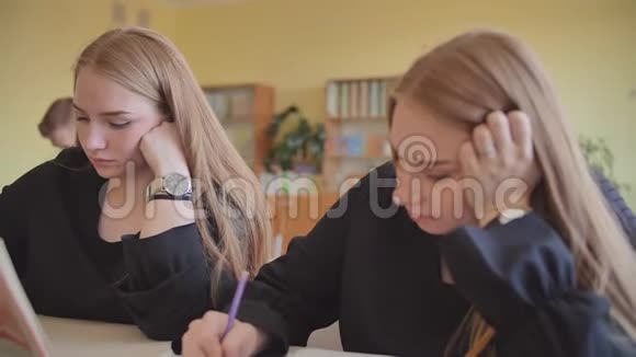 两个双胞胎姐妹在学校的办公桌上视频的预览图
