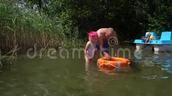 爸爸教女儿和救生圈一起游泳双体船上的儿子万向节运动视频的预览图