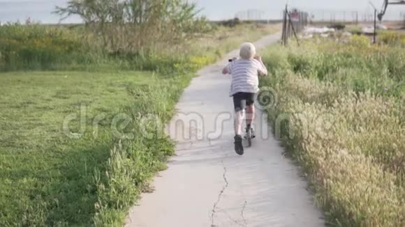 男孩骑着滑板车滚到海里视频的预览图