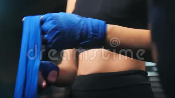 贴身女性用蓝色拳击保护带包裹手准备参加战斗训练视频的预览图
