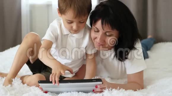 妈妈和小男孩玩游戏或在平板电脑上为孩子们使用应用程序视频的预览图