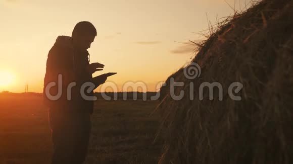 农民使用平板电脑在附近的田野干草堆日落智能农业在农业中使用现代技术视频的预览图
