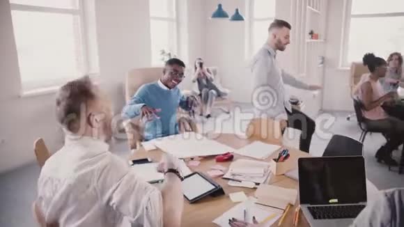 开朗的欧洲年轻CEO在现代办公室用有趣的舞蹈庆祝成功使同事加入慢动作视频的预览图