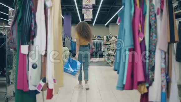 年轻女子正高兴地在服装店里转悠快乐的购物理念视频的预览图