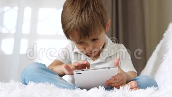 可爱的小男孩花时间玩他的平板电脑视频的预览图