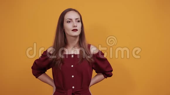 严肃的女人穿着时尚的栗色连衣裙双手放在腰带上看起来很性感视频的预览图