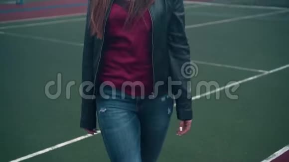 一个美丽而充满激情的女孩在篮球或网球场周围走来走去一个年轻的女人在法庭上散步视频的预览图