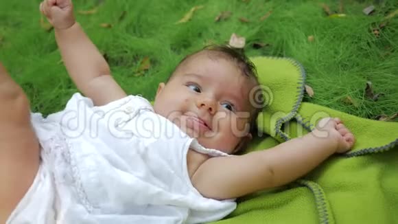 小女孩躺在公园草地上的地毯上梦幻般的新生婴儿躺在户外草地上视频的预览图