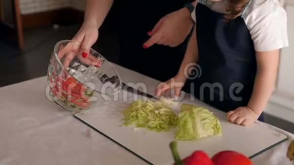 小女孩帮妈妈准备沙拉她把卷心菜放在盘子里视频的预览图