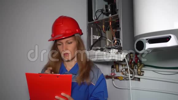 带头盔的认真女工程师检查加热系统的技术数据视频的预览图