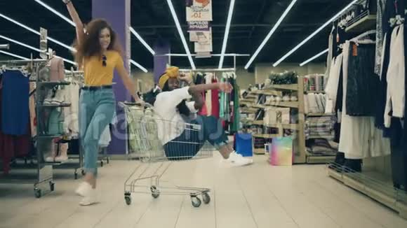 快乐有趣的购物两位漂亮的女士在服装店里用手推车跳舞视频的预览图