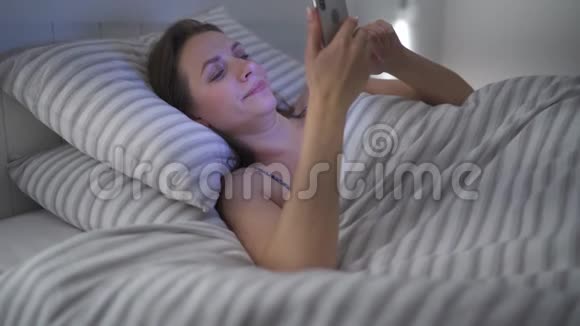 女人躺在床上用智能手机她揉眼睛因为她又累又困手机成瘾或失眠视频的预览图