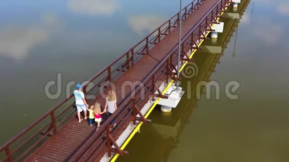 一家人沿着木桥走过湖面空中无人机射击视频的预览图