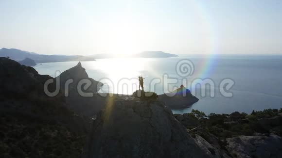 日出时一对年轻的恋人站在山顶上亲吻着海面的空中轮廓飞行航班视频的预览图