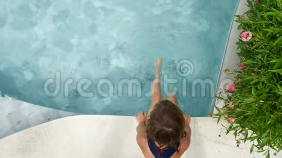 孩子坐在游泳池上挥舞着双腿视频的预览图