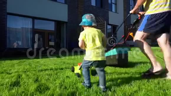 家庭男孩父子在私人院子里割草万向节运动视频的预览图