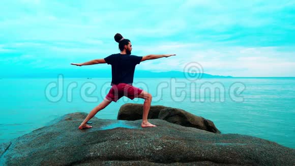 一个男人在海边的大石头上练习瑜伽视频的预览图