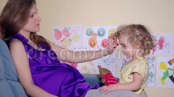 孕妇和女儿带着玩具猫亲吻妈妈肚子视频的预览图
