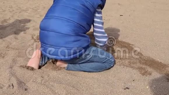 在海滩上玩沙子的男孩视频的预览图