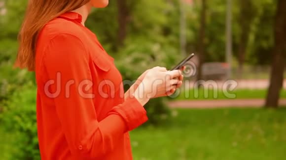 戴着智能手机在街上行走的红发女人视频的预览图