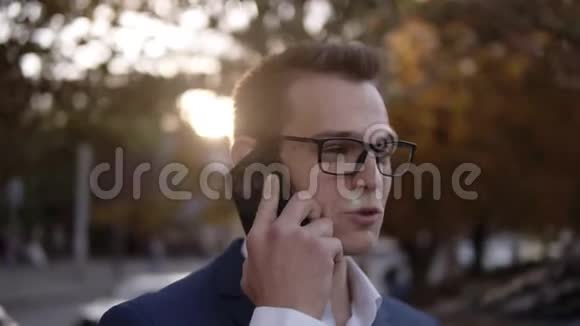 商人戴着时髦眼镜在商业区街头的手机上交谈的肖像年轻的微笑视频的预览图