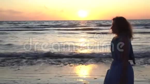 有活力的女人手里拿着凉鞋走在海边视频的预览图