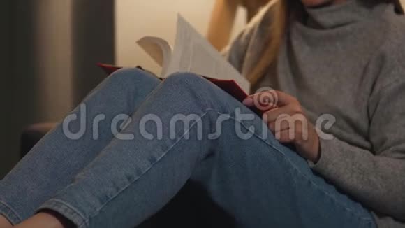 晚上躺在沙发上舒适的房间里看书的女人视频的预览图