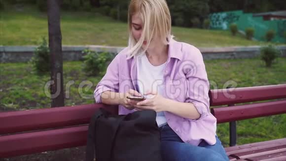 十几岁的女孩用智能手机坐在长凳上发短信视频的预览图