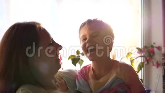 一位母亲把儿子抱在窗前的怀里太阳光线穿过玻璃好心情视频的预览图