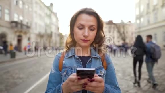 日落时分女人用智能手机走在老街上交流社交网络网上购物概念视频的预览图
